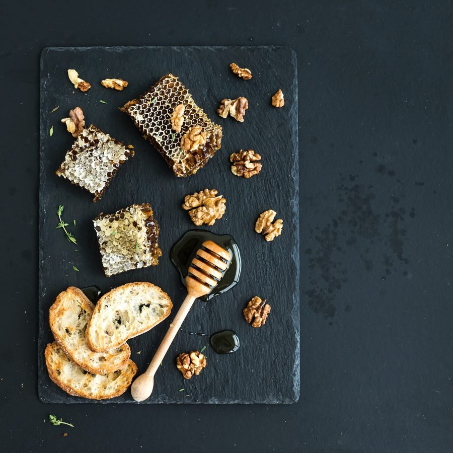 Honeycomb, walnuts, bread slices and honey dipper Honeycomb, walnuts, bread slices and honey dipper